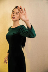 Velvet midi dress with long sleeves, boat neckline, and low back bow detail